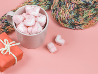 heart shape marshmallows in pink cup  on wth red gift box and  colorful scarf on pink background with copy space.
