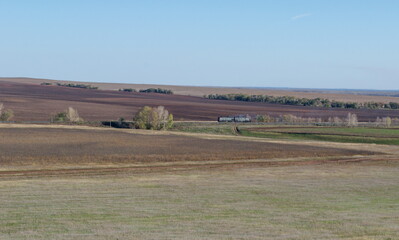 Obraz premium The locomotive goes along the railway line through the steppe expanses. The Orenburg region. Russia.