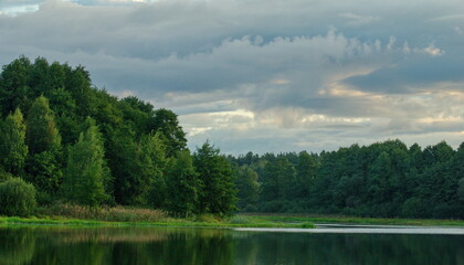 Thunderclouds before rain over a small forest lake. Moscow region. Russia.