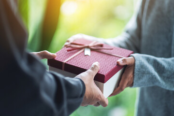 Closeup image of a man giving a woman a gift box