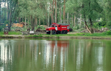 Ramenskoe. Moscow region. Russia. July 03.2018. A team of firefighters on a fire truck control the felling of trees on the lake shore.