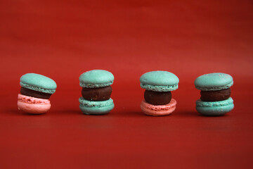mini korean macarons on red colored background. Minimal food photography concept with copy space for text.