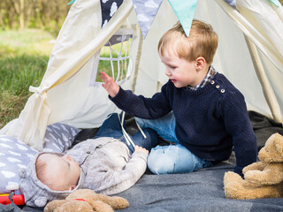 Two little boys - brothers playing in the teepee tent outdoors