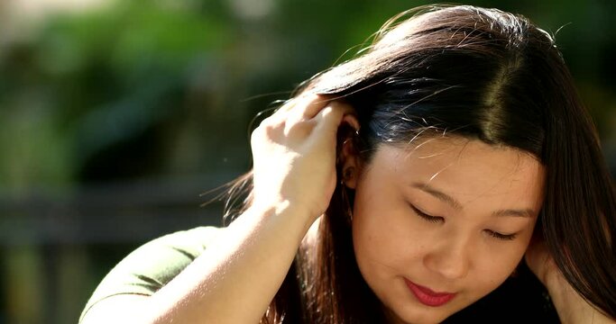Larger size Japanese young woman adjusting hair outside