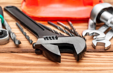 Hardhat with work tools on wooden background.