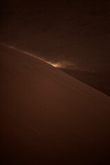 Sand blowing from the top of a Sand dune at first light, Sossusvlei, Namibia.