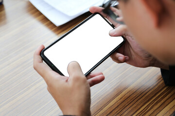 Asian man holding a smartphone with a white screen in the coffee cafe. Smartphone on hand with...