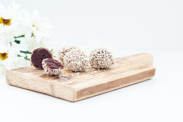Healthy raw energy balls with cocoa, chocolate, flaxseed, on a white textured wooden background.