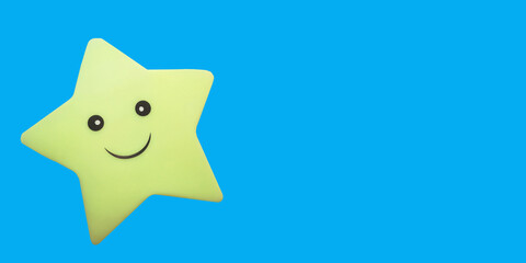 star toy with a smile on a blue background with place for text, copy space. fun kids banner, dream,...