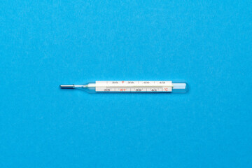 mercury thermometer on blue background - top view with copy space