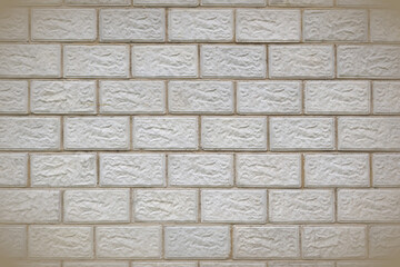 The wall of the building is made of gray concrete blocks. Background with vignetting. The seams form a pattern similar to brickwork. Light backdrop on the topic of housing construction and renovation