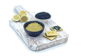 Pistachio matcha white chocolate candies and chocolate and black flax on a wooden board, on a white background.