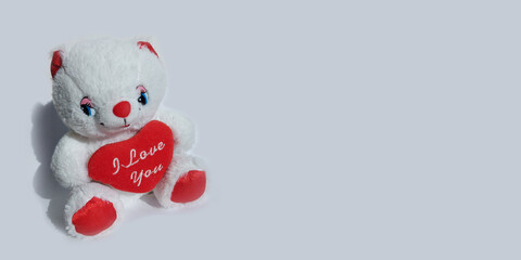 white teddy bear with a red heart on a gray background with place for text. banner, valentines day, love, toy, gift.