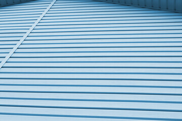 Striped plastic siding surface and piece of cornice. Construction and renovation of buildings. Tinted light blue background or wallpaper. Building materials or technologies
