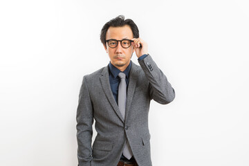 Confident Asian businessman in grey suit and eyeglasses posing standing over white wall background, Business success concept.