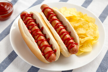 Tasty American Hot Dog with Potato Chips on a white plate, side view.