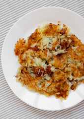 Homemade Fried Hashbrowns on a white plate, top view. Flat lay, overhead, from above.