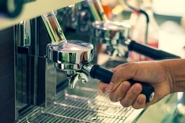 Barista hand grinding fresh roasted specialty coffee in to professional machine.