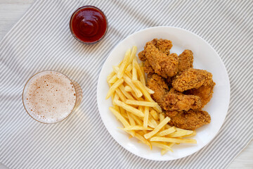 Homemade Crispy Chicken Wings and French Fries with glass of cold beer, top view. Overhead, from above, flat lay.