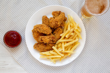 Homemade Crispy Chicken Wings and French Fries with glass of cold beer, top view. Overhead, from above, flat lay.