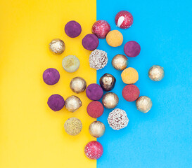 handmade chocolate truffles, different colors on a blue and yellow background.