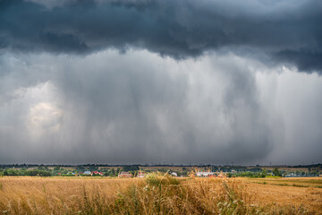 Fototapeta na wymiar A huge storm cloud with a wall of rain in the countryside.
