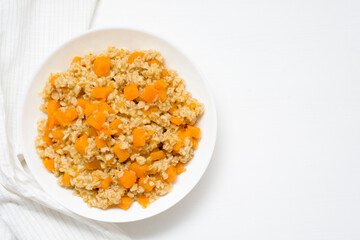 homemade oatmeal porridge with seasonal autumn pumpkin in a white plate on a light background top view .
