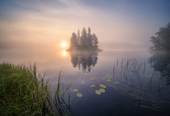 Scenic nature landscape with mood fog and beautiful sunrise at early summer morning in lakeside Finland - 389161132