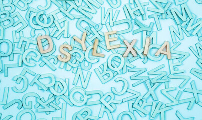 Wrongly spelt Dyslexic word concept background -  jumbled  alphabet letters in turquoise blue  with the word dyslexia spelt wrong on top and space for message 
