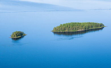Fototapeta premium Scenic lake landscape with blue water and beautiful pine trees island at sunny summer day in National park Finland