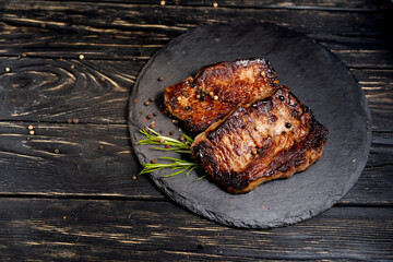 juicy piece of fried meat lies on a stone plate against a black wooden table