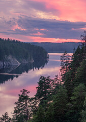 Scenic forest and lake landscape with tranquil mood and colourful sunset at summer morning in Finland