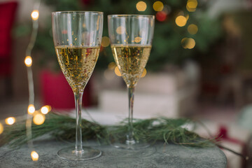 Christmas/New Year background with two glasses of champagne in front of decorated Christmas tree.