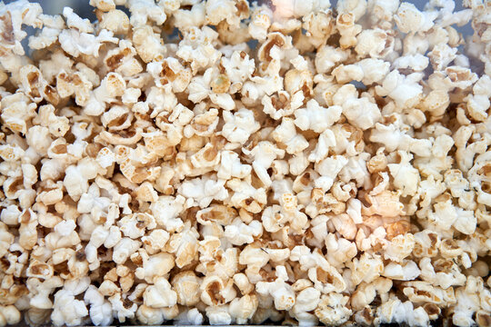 Popcorn background behind glass in a po pcorn maker.