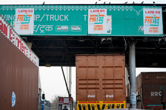 Trucks And Vehicles Waiting At An NHAI Toll Booth With FASTag Cashless Payment Callout