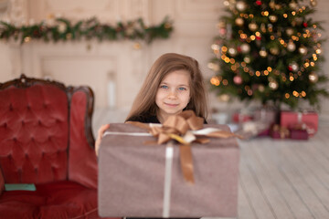 Fototapeta na wymiar A little girl opens a Christmas present from Santa. Christmas tale. Happy childhood