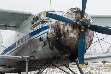 old, vintage plane with a small aircraft propeller at the airfield, airport in the snow in winter