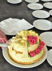 Slicing a beautifully decorated wedding cake covered with marzipan ornaments Vertical photo.