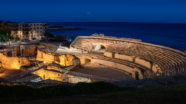 Roman amphitheater illuminated at night. Well-preserved monument in the old city of Tarraco. Inside it there is a Romanesque style church. Tarragona by the Mediterranean sea, Catalonia, Spain