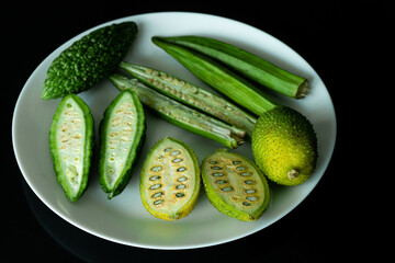 green vegetables in white plate on black background flat lay
