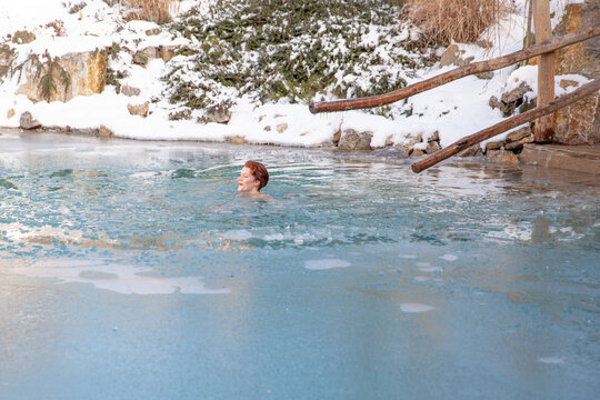 bathing young woman in a frozen lake after sauna