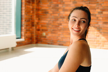 Fototapeta na wymiar Portrait of a brunette. A healthy, strong woman with a happy smile. In the gym during training. Photo with empty side space