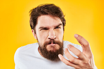 emotional bearded man gesturing with hands aggression discontent close-up yellow background