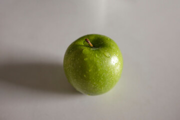 a green apple with drops of water