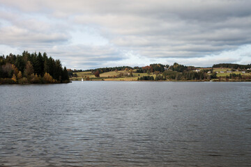 Fototapeta na wymiar Un petit voilier navigue sur le lac de Devesset en automne
