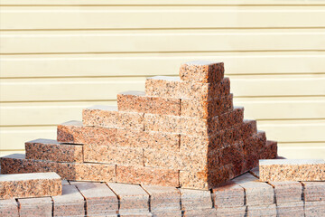 Neat carved blocks of red granite are stacked.