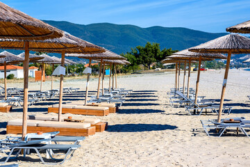 Reed umbrellas and sun beds at the empty beach in Asprovalta, m