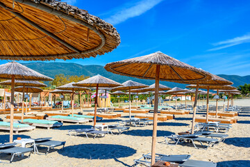 Reed umbrellas and sun beds at the empty beach in Asprovalta
