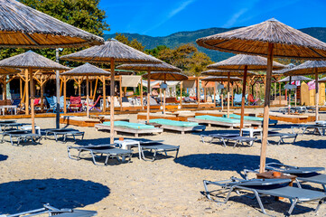 Reed umbrellas and sun beds at the empty beach in Asprovalta