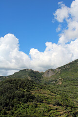 Fototapeta na wymiar Colline delle Cinque Terre con nuvole e il borgo di San Bernardino